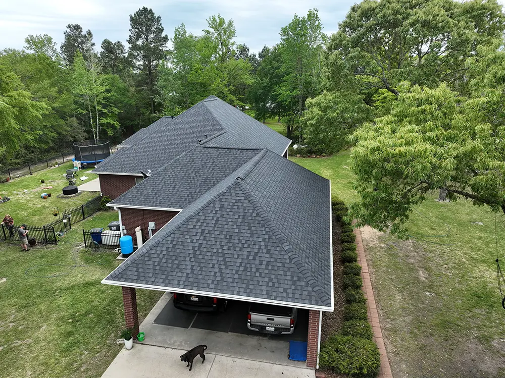 Aerial view of new roof of a home surrounded by trees.