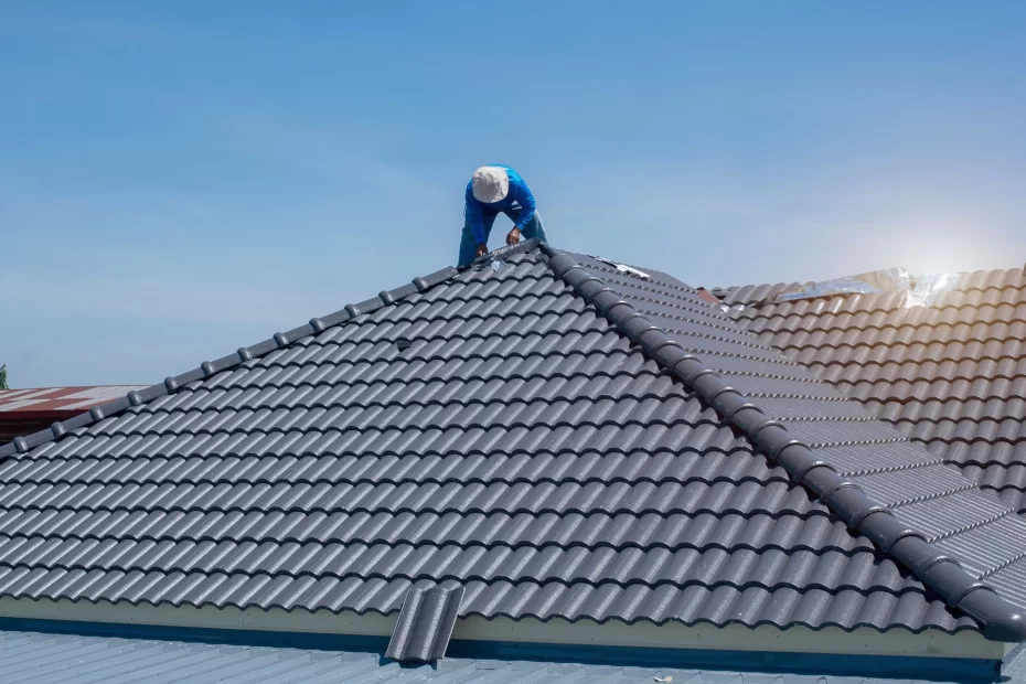 Man in hardhat on top of recently installed metal roof on a house.